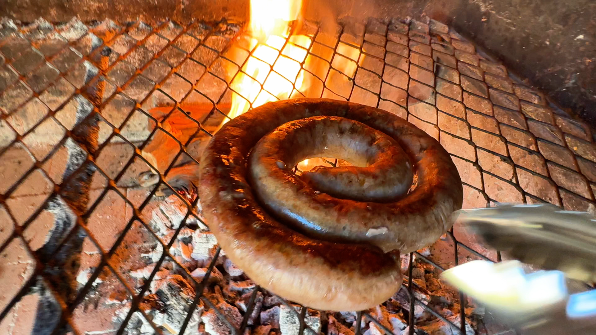 Homemade farm-style boerewors coil braaied over charcoal with pap